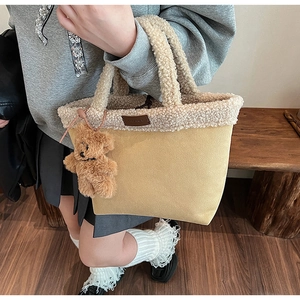Detail of beige fleece tote bag featuring plush lamb wool trim and small brown bear charm