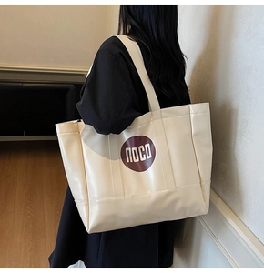 Detailed side view of large cream white PU leather tote bag with round brown printed logo