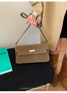 Detail of dark olive suede handbag featuring a vintage silver twist lock and smooth texture