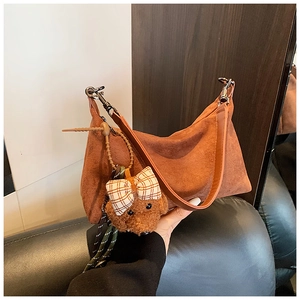 Détail du sac dumpling en daim marron avec pendentif ours en peluche et boucle argentée