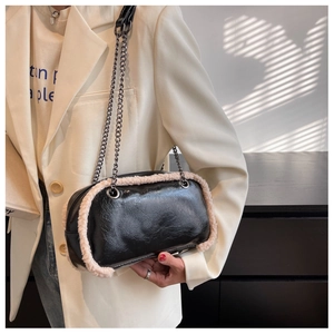 Detail of crossbody bag featuring black glossy leather and cream faux fur trim detailing