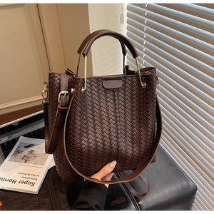 Close-up of dark brown woven texture handbag with golden hardware and leather strap