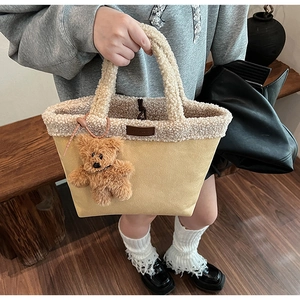 Detail of warm beige faux fur tote bag with plush teddy bear pendant and logo patch