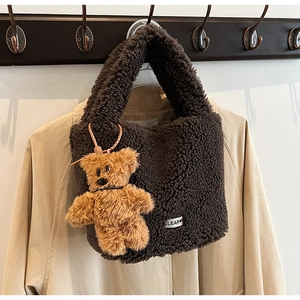 Détail du sac seau en peluche marron avec un charm ours en peluche et étiquette logo