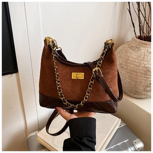 Close-up of suede crossbody bag with rhombus leather stitching and gold chain strap