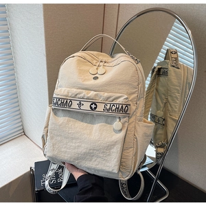Detail of beige nylon backpack showing SJCHAO brand webbing and smooth zipper pulls