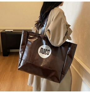 Detail of dark brown tote bag with white noco print and oily leather texture