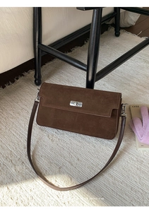Close-up of deep brown suede crossbody bag featuring a silver metal twist lock closure