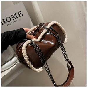 Detail of brown patent leather cylinder bag with white faux shearling trim and chain
