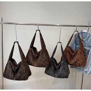 Close-up of four colors of leopard print suede tote bags on hangers with denim jacket