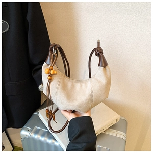 Detail of beige hobo bag with woven strap, suede texture and wooden gourd pendant decoration