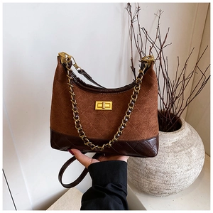 Close-up of brown quilted suede bag with gold metal chain and rectangular twist lock