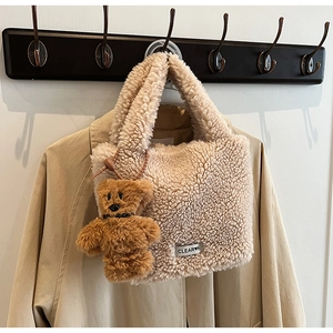 Vue détaillée du sac seau beige en fausse fourrure avec porte-clé ours en peluche marron