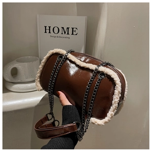 Detail of dark brown patent leather crossbody bag with plush faux fur trim and metal chain