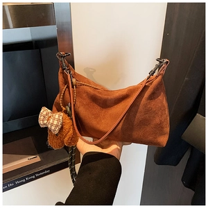 Détail du sac dumpling en daim caramel avec un pendentif ours en peluche et boucle