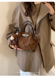 Close-up of leopard print bucket bag with leather handle and cute monkey keychain detail