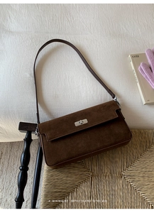 Close-up of brown suede shoulder bag featuring a silver metal twist lock on rectangular flap