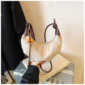 Detail of cream canvas crescent bag with knotted brown leather handle and wooden beads