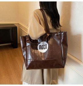 Detailed view of dark brown tote bag showing glossy leather texture and white NOCO logo