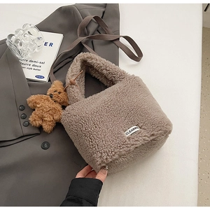 Détail du sac seau en peluche marron avec charm ours en peluche et étiquette logo