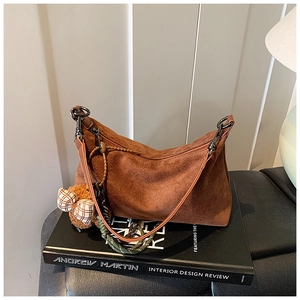 Détail du sac dumpling en daim marron avec zip bronze et breloque ours en peluche