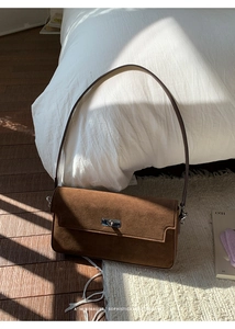 Detail shot of the matte brown suede texture with elegant silver metal twist lock closure