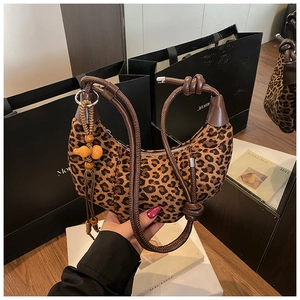 Close-up of leopard print crescent bag with woven rope strap and gourd pendant
