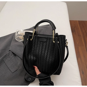 Detailed view of the black woven bucket bag with leather texture and gold metal hardware