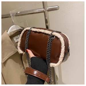 Detail of dark brown patent leather bag with white faux fur trim and dual chain strap