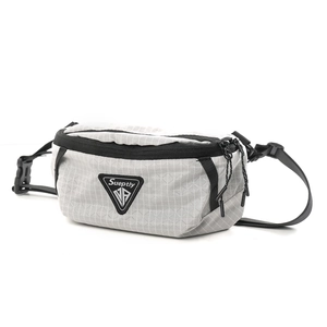 Close-up of light grey checkered cross-body bag featuring dual zippers and logo patch