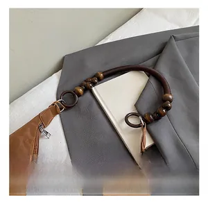 Detail of vintage brown suede tote bag with unique dark wooden bead handles and metal rings