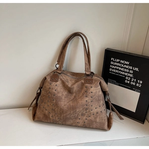 Détail des clous argentés et de la texture cuir vintage du sac cabas marron