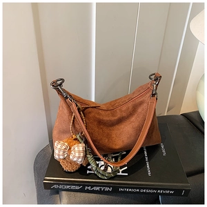 Détail du sac à main en daim caramel avec pendentif ours en peluche et bandoulière