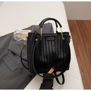Close-up of black woven leather tote bag with gold metal handle and luxury texture
