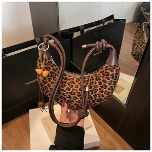 Detail of leopard print crescent bag featuring leather knot handle and beaded tassel