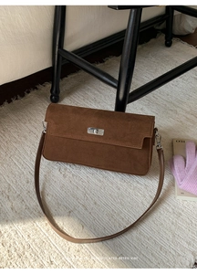 Detailed macro view of the brown suede crossbody bag showing the silver metal twist-lock buckle