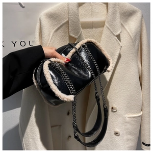 Detail of glossy black patent leather bucket bag with plush white faux fur trim and chain