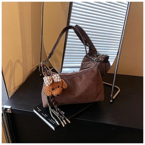 Détail d'un sac dumpling en daim marron foncé avec un joli pendentif chien en peluche