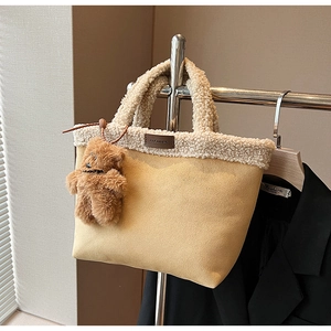Detail of fuzzy beige tote bag with white faux shearling trim and brown bear charm