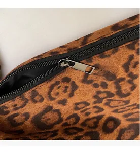 Detail view of smooth black zipper and silver hardware on leopard print suede tote bag
