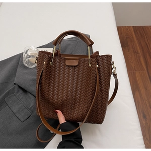 Close-up of dark brown woven leather texture and golden hardware on the bucket bag