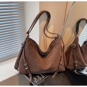 Detail of brown matte leather tote bag with silver buckles and retro strap design