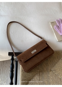 Close-up of a brown suede shoulder bag featuring a vintage metal turn-lock and retro vibe