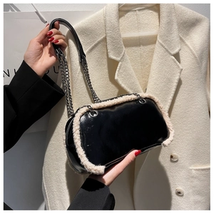 Close-up of black glossy leather crossbody bag with white faux shearling trim and chain