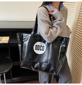 Detail of the high-shine black tote bag featuring a prominent white NOCO logo on the side