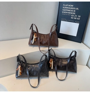 Detail view of retro leather hobo bags with decorative wooden bead charms and wrinkled texture