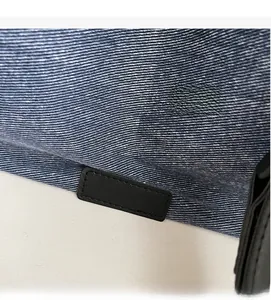 Macro shot of denim fabric texture and black leather patch with reinforced stitching