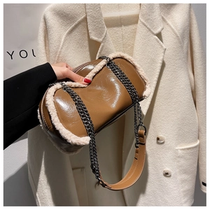 Close-up of brown glossy cylinder bag featuring white faux fur trim and metal chain strap