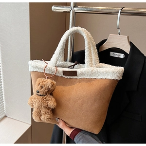 Detail of faux shearling trim and suede tote bag with a cute plush bear pendant