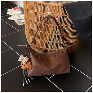 Gros plan d'un sac hobo en daim marron foncé avec un joli pendentif ours en peluche